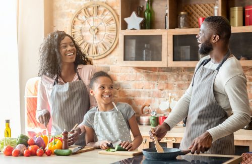 Happy black family of three laughing at kitchen